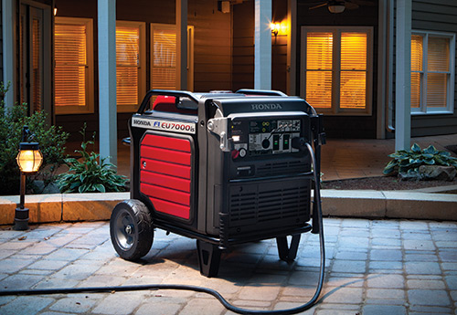 Honda EU7000is connected to a 30A plug on paved floor in a backyard