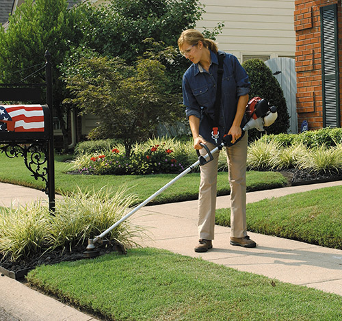 Women trimming weeds in her front yard with a Honda Trimmer